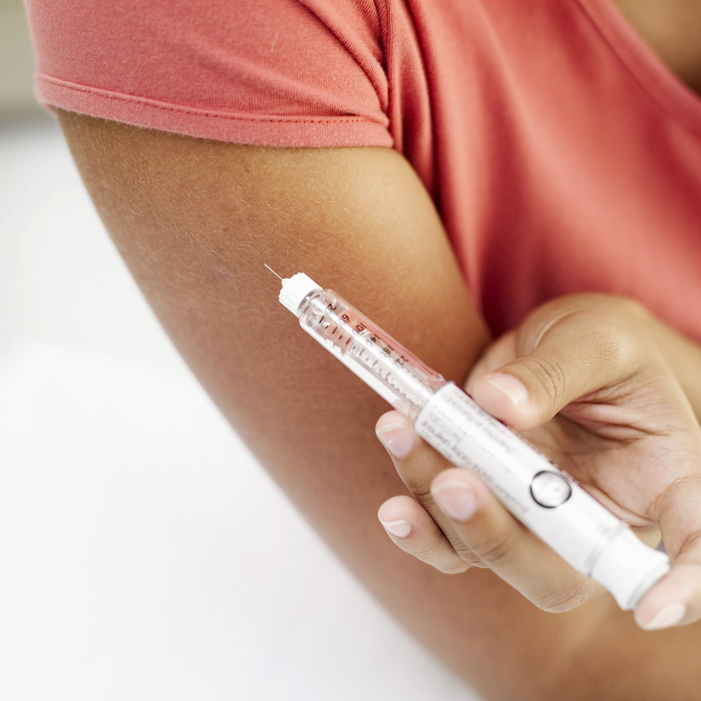 Person Self-Administering an Injecting in the Arm